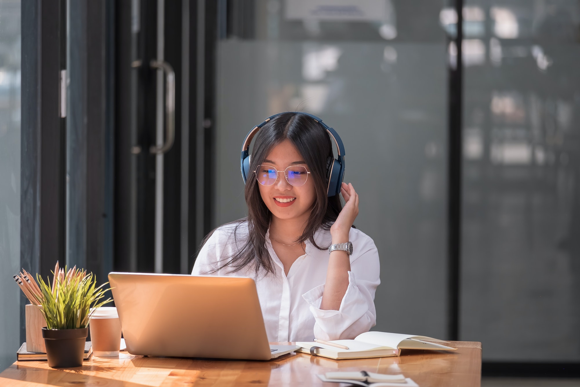 Asian girl with glasses look at laptop while doing homework making video call abroad using internet-letsworkabroad